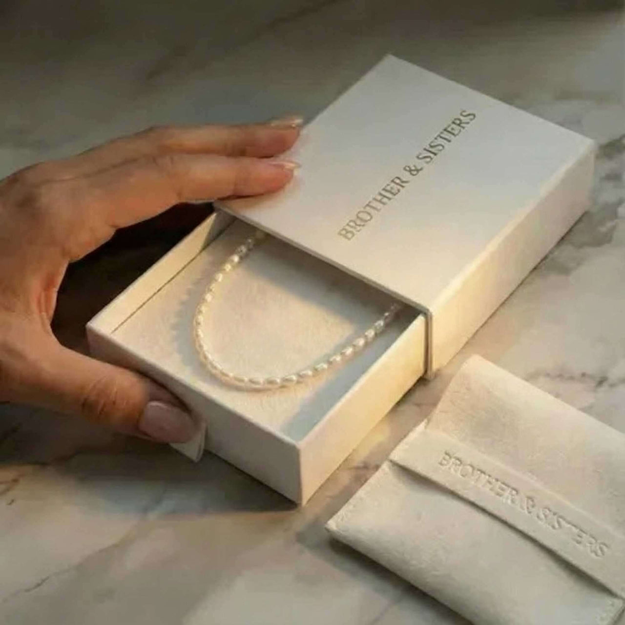 Freshwater Pearl Choker by Brother & Sisters nestled in elegant packaging with a hand holding the box.