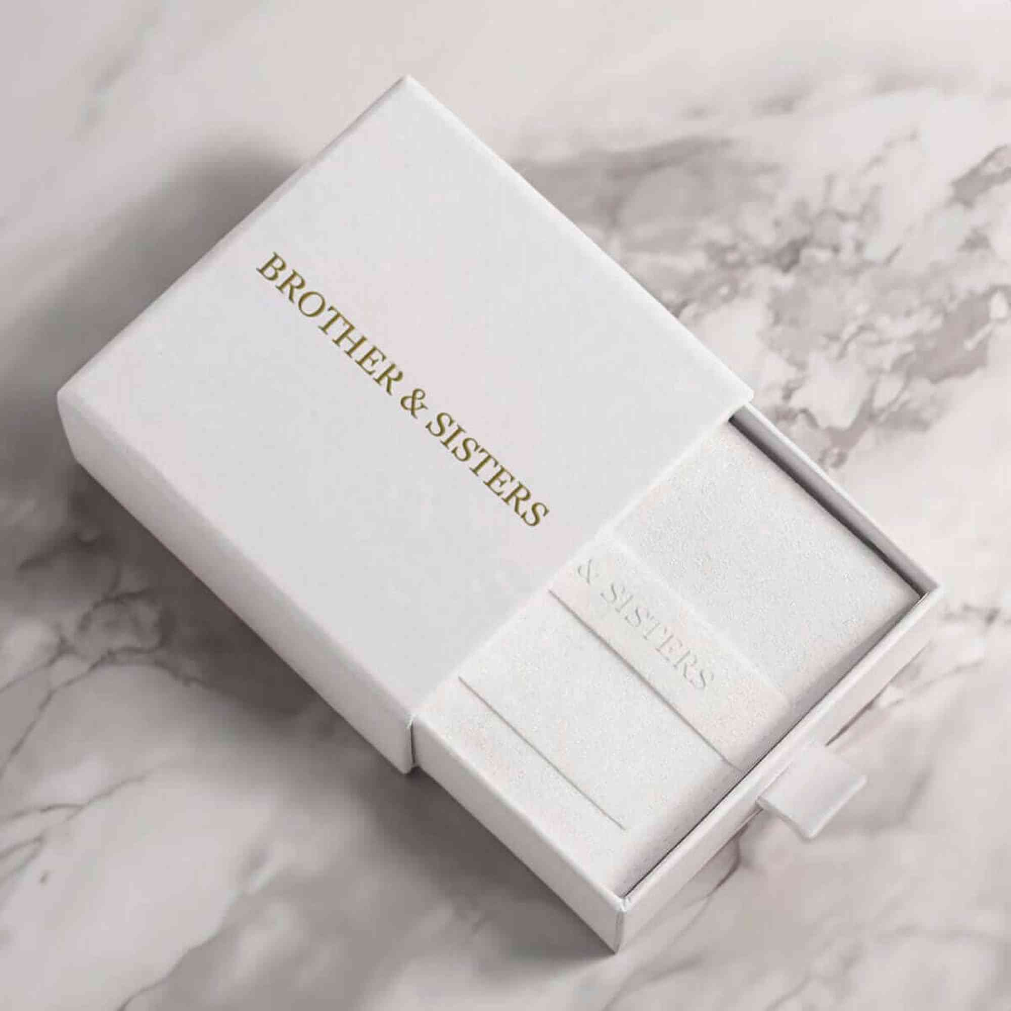 Elegant packaging of Brother & Sisters for the Sunflower Photo Necklace, featuring a white box with gold lettering.