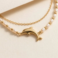 Thumbnail for Close-up of the Pearl Dolphin Anklet Set: gold dolphin charm set between freshwater pearls, with a fine gold cable chain, by Brother & Sisters.