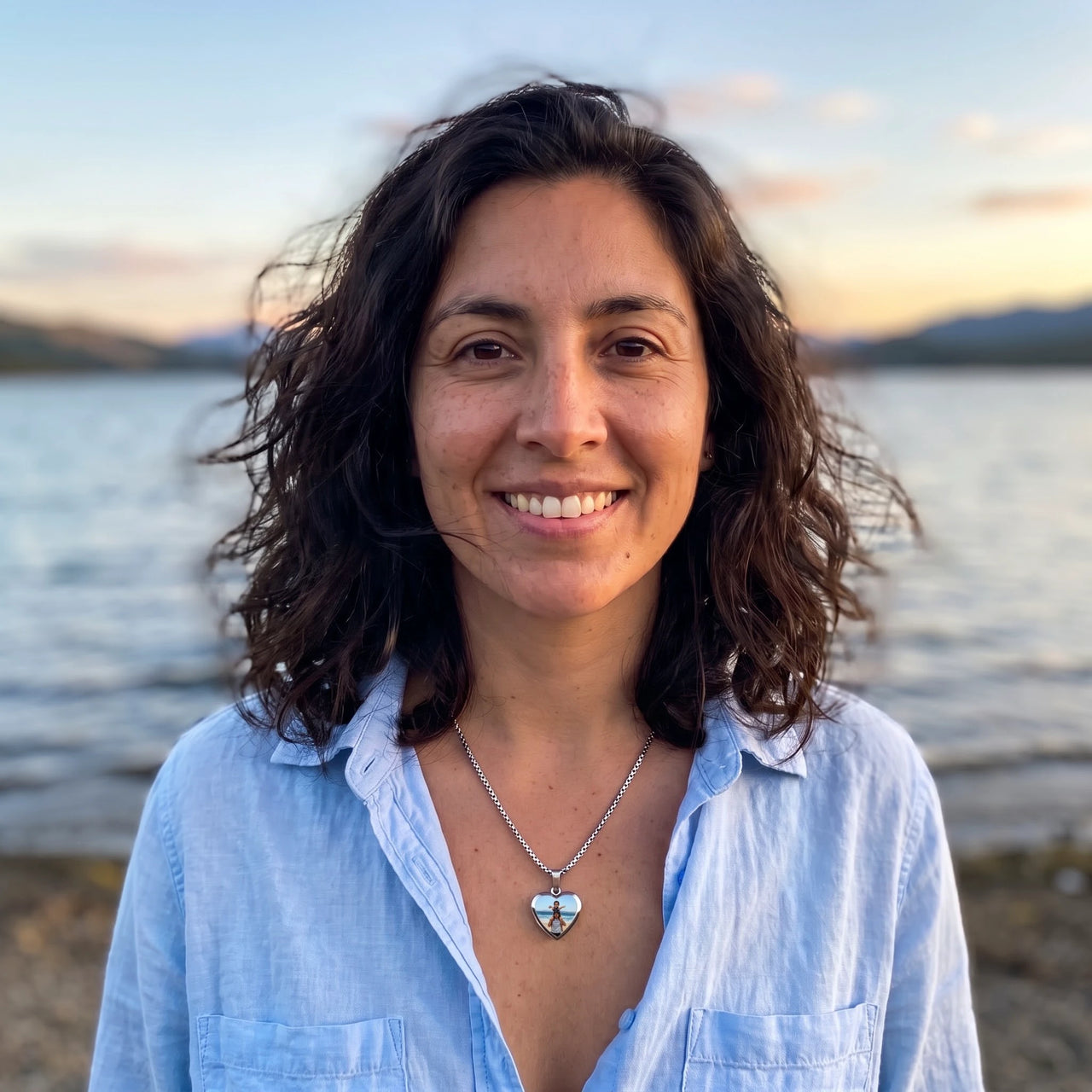 Woman by a lake at sunset wearing the silver secret heart photo necklace | SKU: TPH-CHTN-SILVER-SMALL
