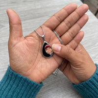 Thumbnail for Thumb warming the silver teardrop pendant: the hidden photo appears under the thumb while the rest stays black | SKU: TPH-DRPN-SILVER