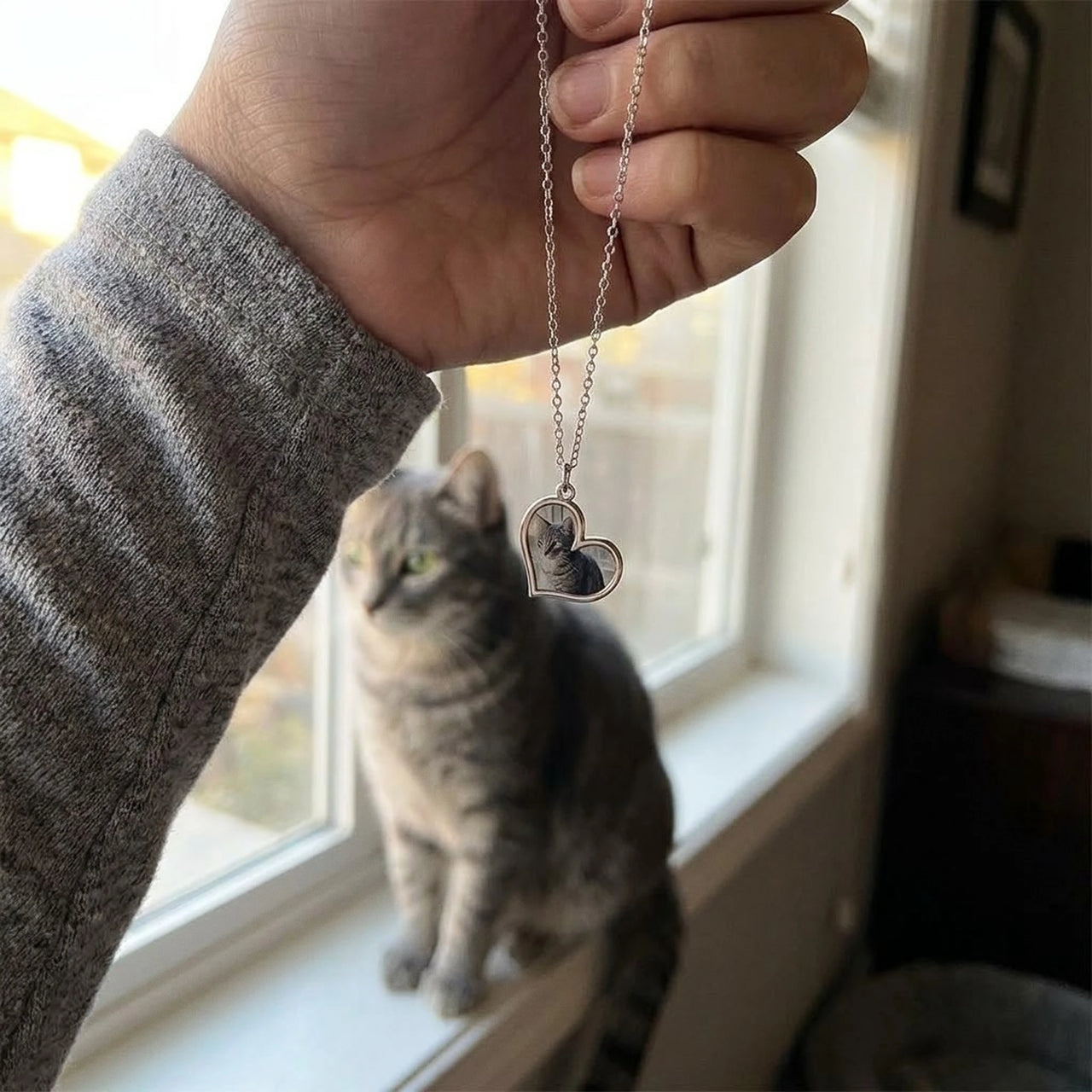 Customer photo: the silver secret heart necklace with her cat's photo, her cat in the background | SKU: TPH-HRTN-SILVER